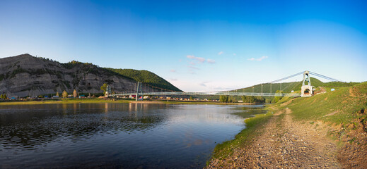 Obraz premium Southern Urals, Bashkortostan, suspension bridge in the village of Tash-Asty. The Zilim River and the Ukly Kaya rock.