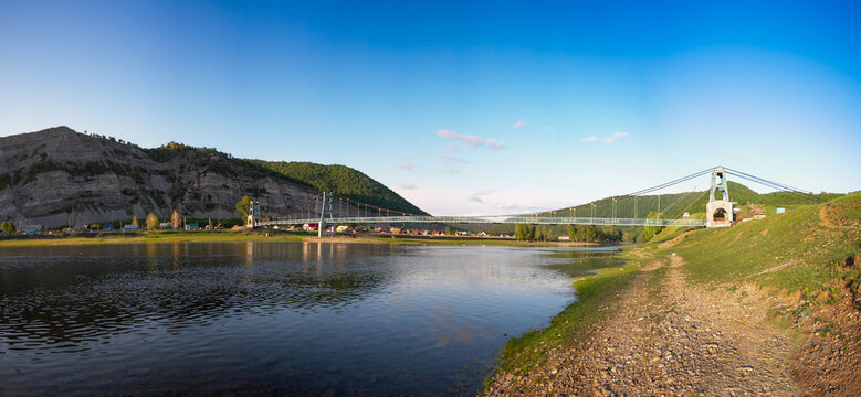 Southern Urals, Bashkortostan, suspension bridge in the village of Tash-Asty. The Zilim River and the Ukly Kaya rock.