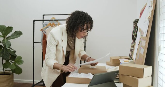 Diverse team opening boxes, checking garments, labeling shipments, hanging apparel in studio