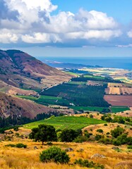 Fototapeta premium A landscape with rolling hills, green fields, and distant ocean