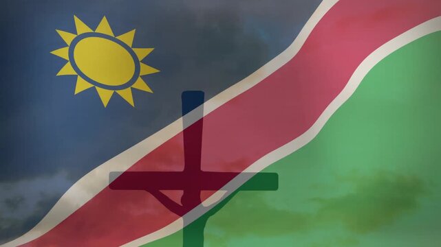 Namibian flag rippling in wind, cross-shaped silhouette overlying flag while clouds drifting