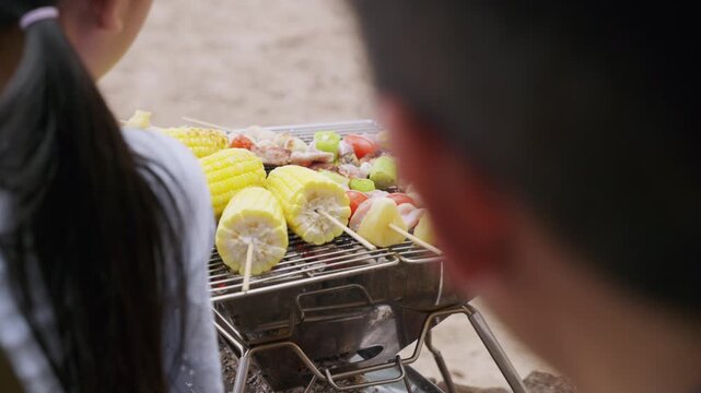 Family tent camp summer eat food vacation offers happy travel moments, grilling delicious skewers with corn pineapple meat and meatballs for truly enjoyable outdoor picnic experience.
