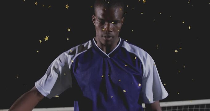 Male player raising leg over soccer ball, preparing control as camera pulling up, stars drifting