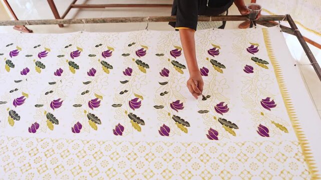 Artisan hand painting traditional Indonesian batik fabric