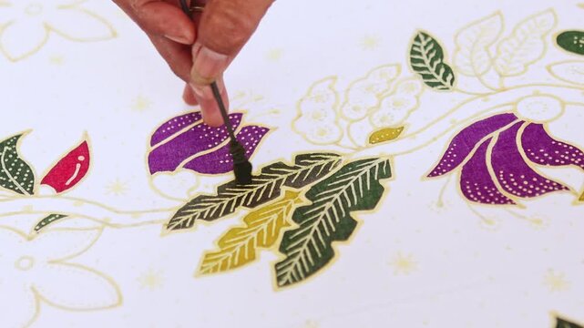 Indonesian artist painting traditional batik fabric