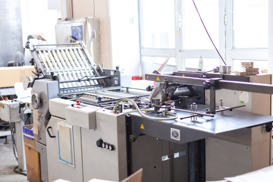 Folding machine in print shop used to accurately fold printed sheets into brochures, leaflets, signatures and inserts. Industrial paper folding equipment for commercial printing production.
