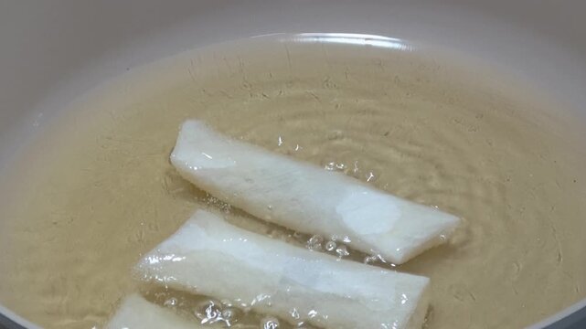 The chef is putting spring rolls into the fryer.