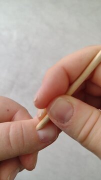 first person vertical video of pushing back cuticle with wooden orange stick. detailed manicure step, precise slow hand movement. clean nail care b-roll for beauty, salon and skincare ads.