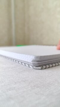 Low angle close-up video of notebook pages being quickly flipped at table level. Dynamic page movement, paper texture detail, study or planning concept, minimal indoor lifestyle footage.