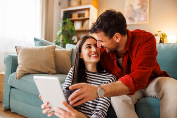 Obraz premium Couple drinking coffee and using tablet computer at home