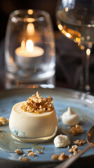 Exquisite Gourmet Panna Cotta Dessert with Honey Glaze and Topped with Toasted Walnuts, Served on a Blue Ceramic Plate in a Romantic Candlelight Restaurant Setting with Glass of White Wine Background