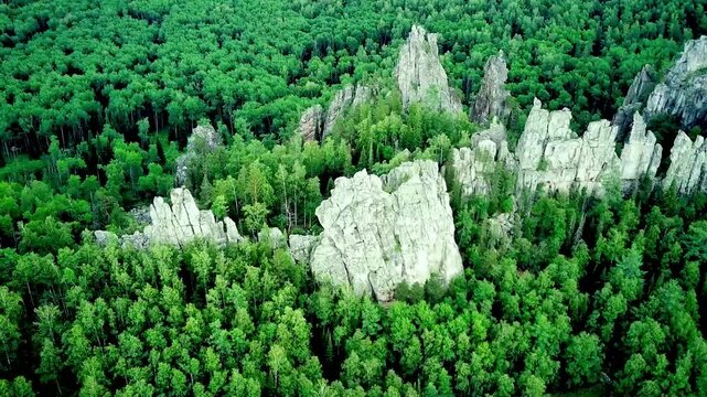 Bird's eye view on mixed green forest and rocks from mountain during summer day. Aerial view of a through deep forest. Bird eye view of a Green Forest road. Drone shot.
