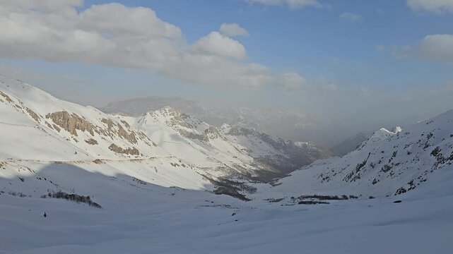 Breathtaking winter mountain valley: vast snow-covered slopes and rugged peaks fade into misty distance under expansive blue sky with scattered clouds.
📍Hawraman Takht, Kurdistan 