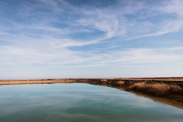 Obraz premium Minimal panoramic view of calm freshwater reservoir reflecting soft blue sky. Peaceful rural environment with clean horizon and open copy space.