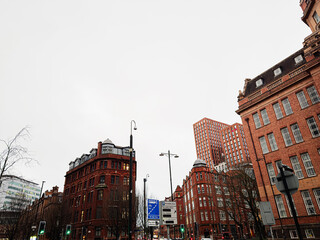 Fototapeta premium Urban landscape in Manchester featuring red brick buildings and modern high rise against cloudy sky