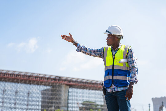 Civil engineer pointing towards progress at an elevated highway and bridge construction project, Confident project engineer gesturing and directing operations at a major infrastructure site