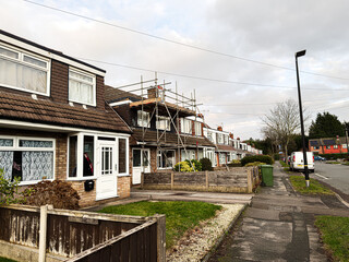 Obraz premium Suburban street with row houses under scaffolding in Manchester, UK, daytime scene.