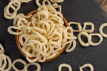 onion rings made from onion puree and flour fried in a large amount of sunflower oil , crispy delicious high-calorie onion rings made from natural ingredients, poured in a wooden bowl