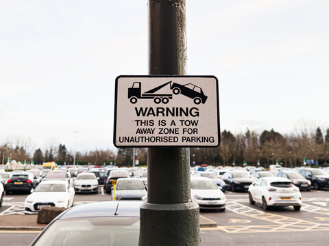 Warning sign in Manchester parking lot about tow away for unauthorised parking