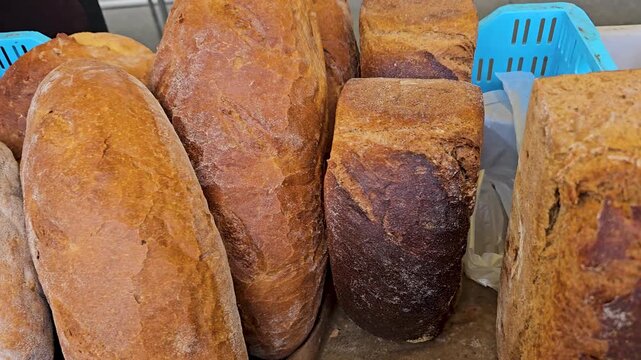 Freshly baked bread displayed in a bakery with various types and shapes arranged on a table in the morning light