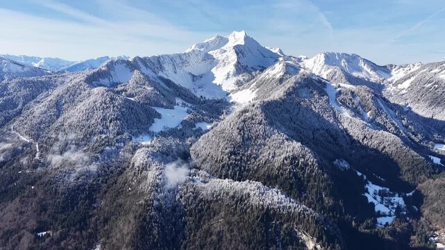 Slow forward aerial drone flight toward Roc d&rsquo;Enfer peak, snow-covered French Alps
