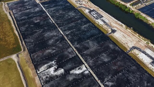 Aerial top view of people working on traditional salt mining fields industry in Vietnam.