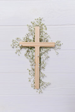 Wooden cross decorated with gypsophila flowers on a white vectical background for easter and good friday celebrations copyspace