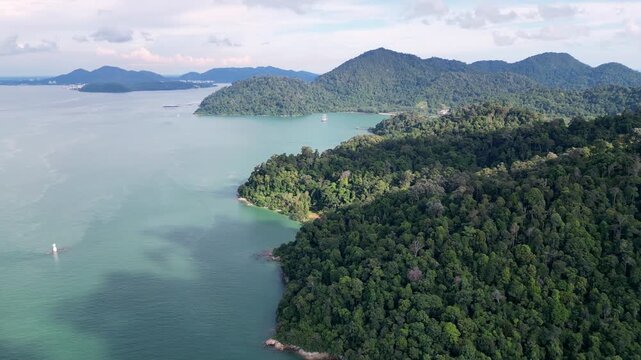 Aerial shot highlights Pulau Pangkor Island, fishing boats floating in turquoise sea beside lush greenery.