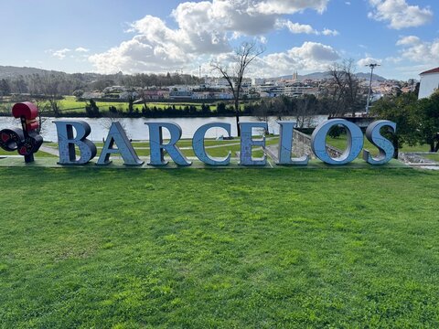 Barcelos sign on grassy hillside overlooking river and townscape under cloudy sky
