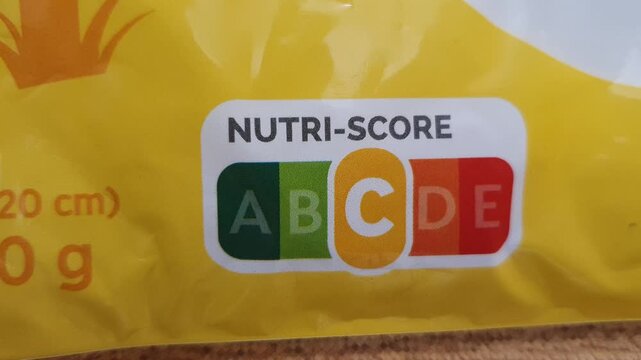 Horizontal closeup panning camera motion over a package of food with a C level in the nutri score scale. 