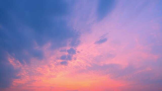 A dramatic sunset sky timelapse video capturing towering cumulonimbus and scattered altocumulus clouds glowing in pink and orange hues against a fading blue evening sky.
