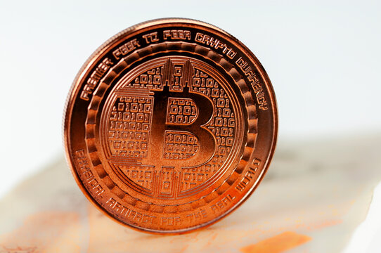 A copper Bitcoin sits on top of a Bank of England ten pound note.