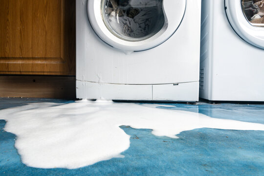 Soap bubbles pour out of a leaking washing machine.