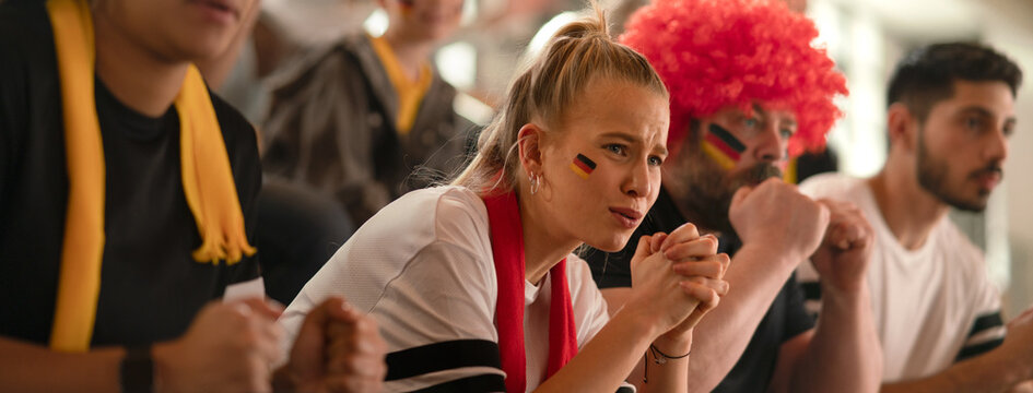 Worried football fans supproting German national team in soccer match at stadium.