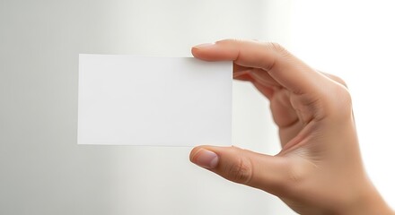 Obraz premium A hand holding a blank white business card against a plain background.