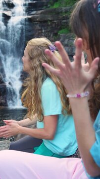 Happy mother and daughter talking by a forest waterfall in Norway. Bright northern daylight, authentic family bonding and sustainable travel concept.
