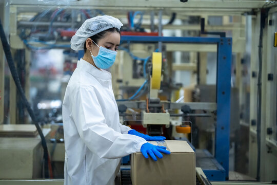Packaging operator positioning shipping box on conveyor belt in factory