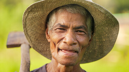 Happy indonesian farmer man, smiling, looking at camera, wearing straw hat, holding a shovel, grey hair and wrinkles, aging farming population, flores island, indonesia, southeast asia, asian people,  © Spice Footage
