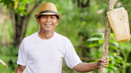 Portrait, smiling indonesian farmer on farm looking at camera wearing hat on flores island,...
