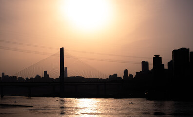 Obraz premium The silhouettes of city skyline surrounded by the sea under the sunlight during the sunset in Chongqing, China