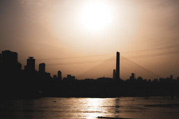 Obraz premium The silhouettes of city skyline surrounded by the sea under the sunlight during the sunset in Chongqing, China