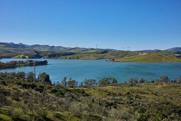 Fototapeta premium Lake with wind farm on green rolling hills