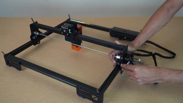Close-up of cable connections on laser engraving system as man plugs in and secures wiring for operation