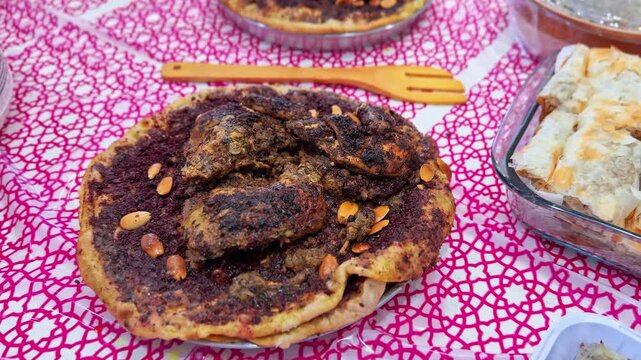 Close-up of traditional Palestinian musakhan featuring spiced roasted chicken served over taboon bread with caramelized onions and toasted almonds, displayed on a festive table setting.
