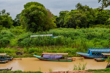 Wooden boats moored on a muddy riverbank in Cambodia
