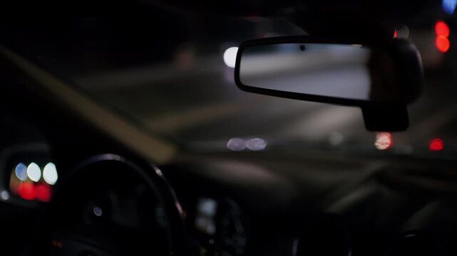 Close perspective of a car interior at night with dashboard details and windshield reflections