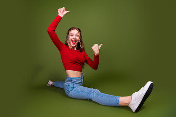 Young woman in red crop top sits on green backdrop smiling with energy and excitement