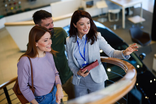 Sales agent showing new car to young couple