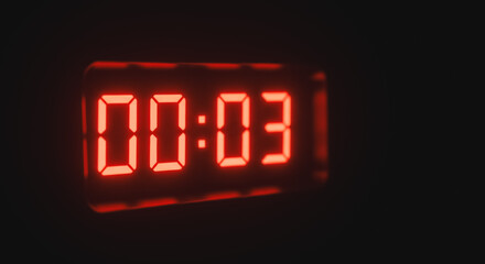 Red glowing digital clock display showing 00:03 on a dark background, representing a countdown, timer, or specific time.