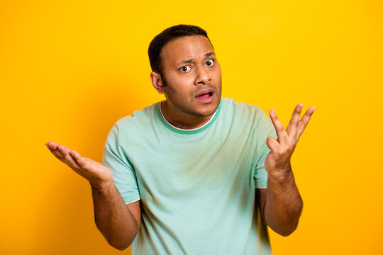 Young man puzzled expression gestures on bright yellow background for casual lifestyle